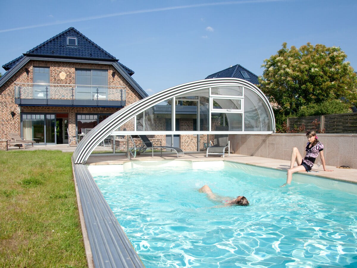Pool with flexible cover and sunbathing area
