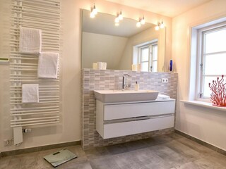 Das Bad ist mit einer Badewanne und einer Dusche ausgestattet.