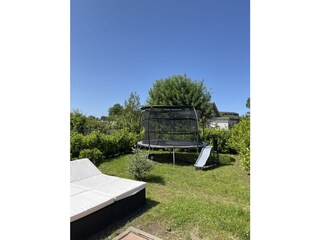 Garten mit Sonnenliegen und Trampolin