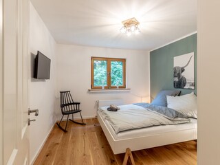 Schlafzimmer mit Doppelbett und Fernseher