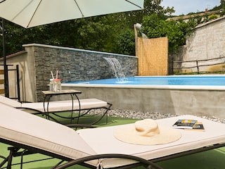 Luxuriöses Badeerlebnis mit sanftem Wasserfall am Pool.