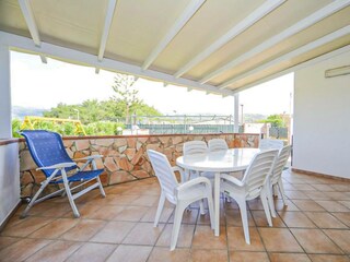 Die überdachte Terrasse mit Esstisch und Gartenmöbeln