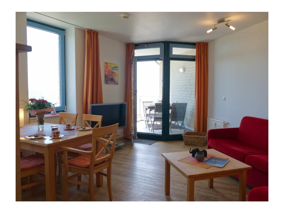 Wohnzimmer mit Esstisch und Tür zum Balkon der Ferienwohnung in Burgtiefe