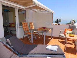 der Balkon mit zwei Esstischen und zwei Sonnenliegen