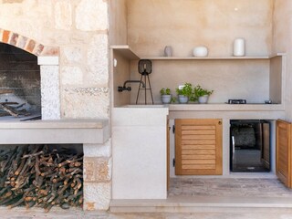 A summer kitchen with a stove, a wine cooler