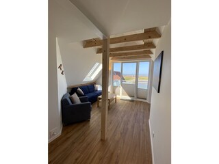 Blick in Wohnbereich mit offenen Balken und Balkon