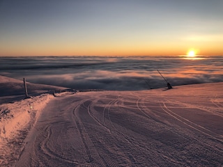 Skifahren über den Wolken im Sonnenaufgang