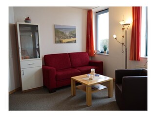 Wohnzimmer mit Couch und Sessel in der Ferienwohnung Inselblume 03 auf Fehmarn