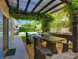 Covered terrace with wooden benches and a dining table