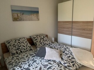 Das Doppelbett im hellen Schlafzimmer & Kleiderschrank.