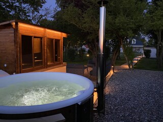 Outdoor wellness area with a hot tub and a 90° sauna