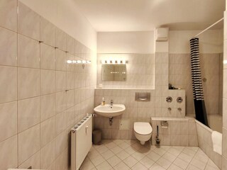 Modernes Badezimmer mit Badewanne und hellem Fliesenspiegel in Koserow