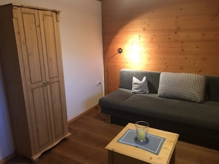 Seperates Wohnzimmer mit Schlafcouch und Fernseher