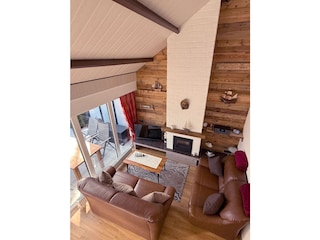 Offener Wohnbereich mit Holzwand, sichtbaren Balken und