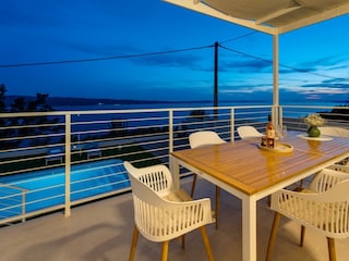 The outdoor dining area is next to the pool, with an am