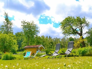 Garten mit Sonnenliegen und "Lilla Huset" (Gästehaus)