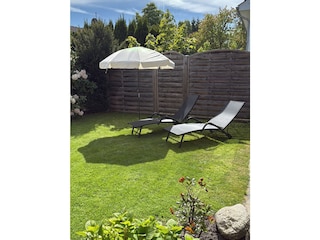 Grünfläche mit Liegen beim  Wintergarten
