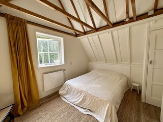 Schlafzimmer mit Holzboden,Vorhängen und bequemen Bett