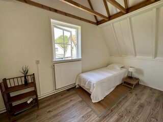 Schlafzimmer mit Holzmöbeln und großen Fenstern
