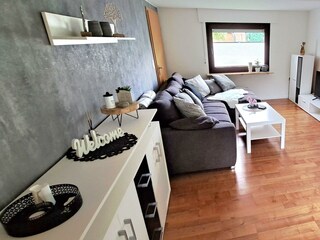 Wohnzimmer mit Schlafcouch und Essecke