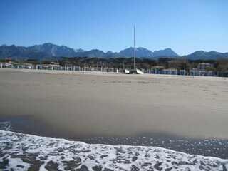 Breiter Sandstrand mit Blick zu den Apuanischen Alpen