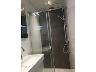 Waschbecken und Regendusche mit Glasabtrennung