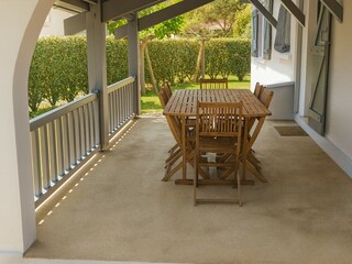 Überdachte Terrasse mit Gartenmöbeln aus Holz