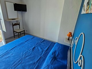 Schlafzimmer mit Doppelbett und TV