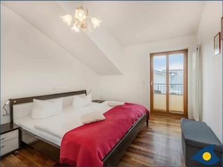 Schlafzimmer mit Doppelbett und kleinem Balkon