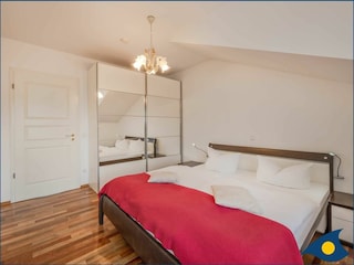 Schlafzimmer mit Doppelbett und kleinem Balkon