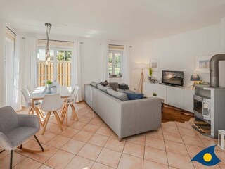 Wohnzimmer mit Kamin, offener Küche und Zugang zur Terrasse