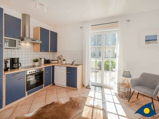 sonniges Wohnzimmer mit Kamin, offener Küche und Zugang zur Terrasse