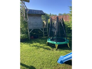 Holzhaus und kleines Trampolin im Garten