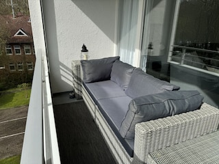 Sonniger Balkon mit gemütlicher Outdoor-Couch