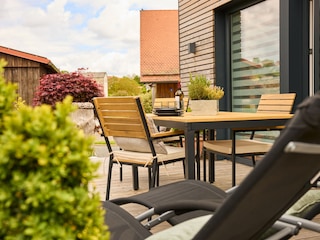 Große Holzterrasse mit Liegestühlen und Sonnenschirm