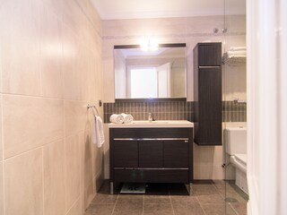 Badezimmer mit begehbarer Dusche, Waschbecken und Toile