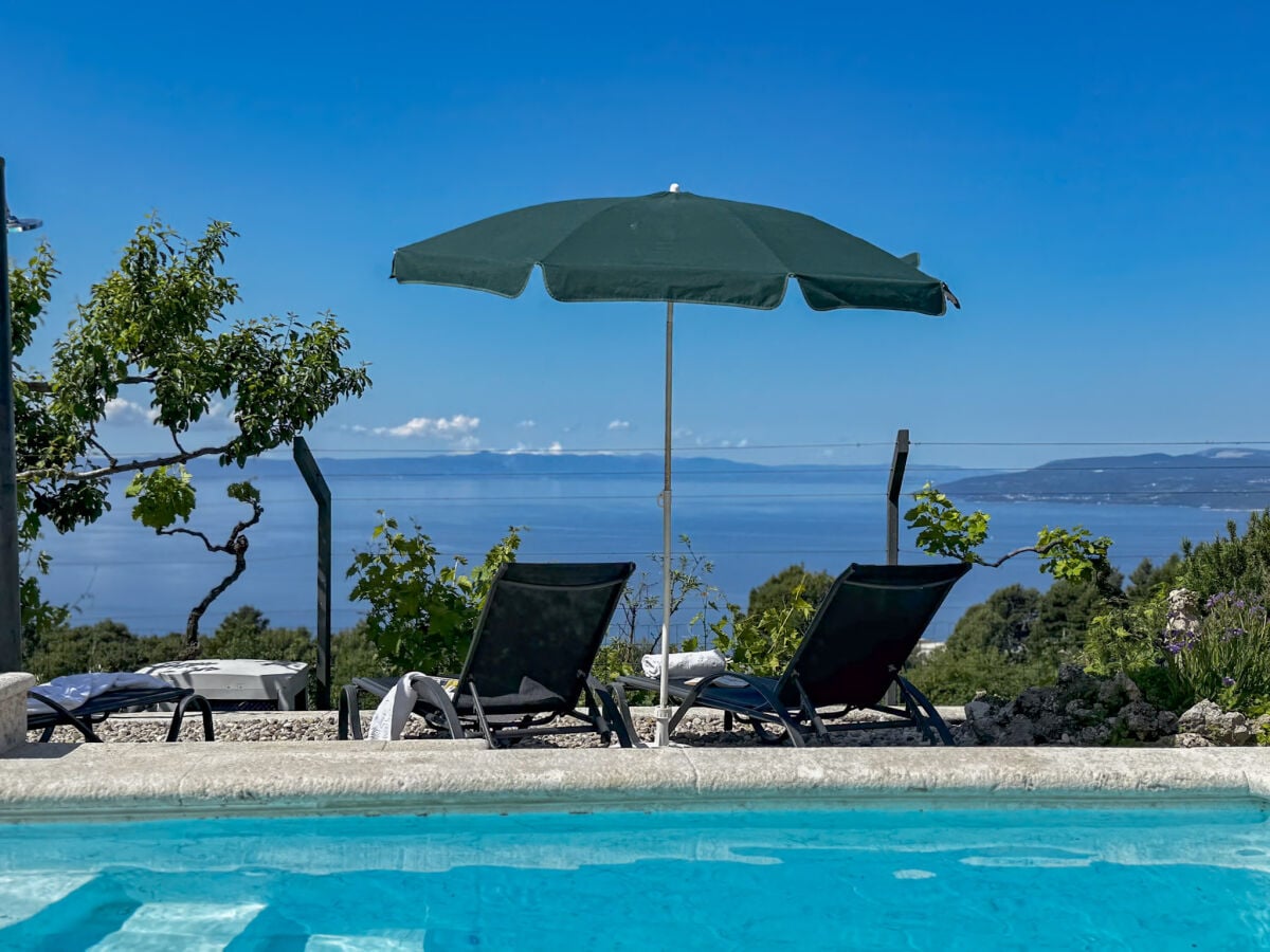 der Pool mit Sonnenliegen und Meerblick