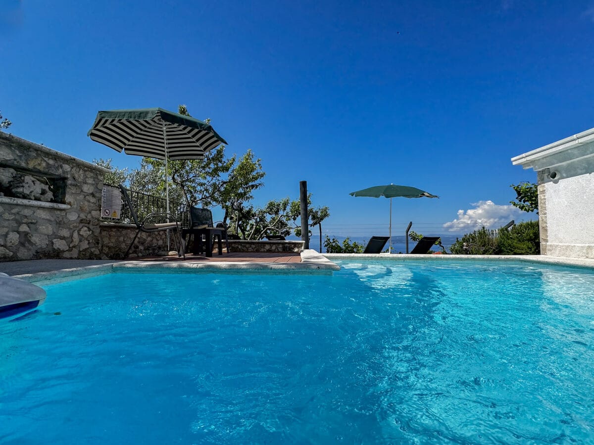 der Pool mit Sonnenliegen und Meerblick