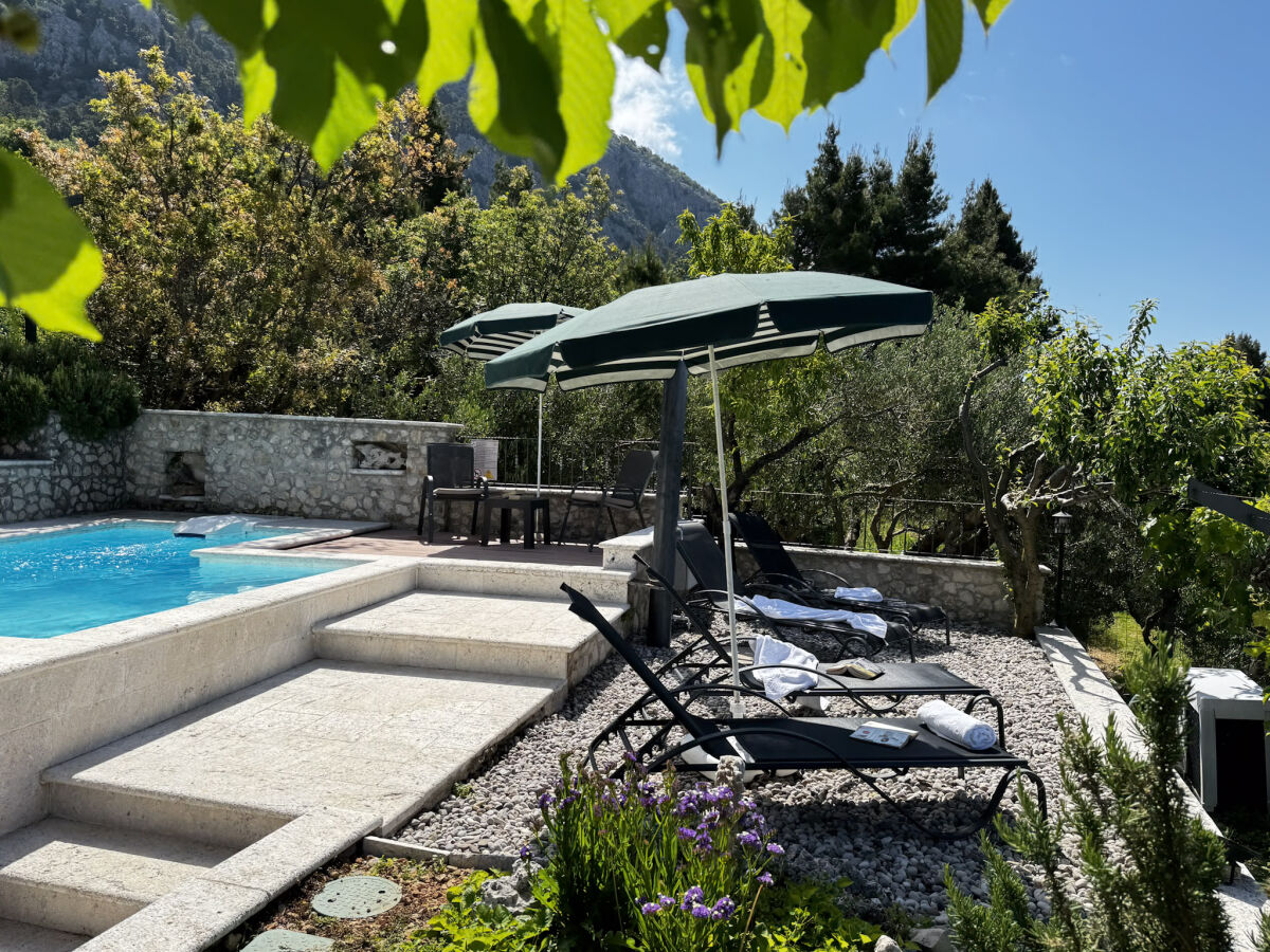 der Pool mit Sonnenliegen und Meerblick