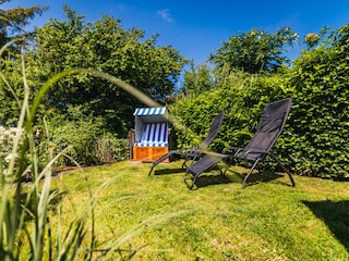 Eingezäunter Garten mit Strandkorb und Sonnenliegen