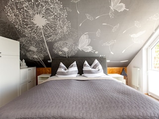 Schlafzimmer mit Boxspringbett, Babybett und Balkon