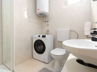 Bathroom with shower, heating, and washing machine.