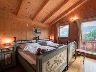 Schlafzimmer mit Doppelbett und Zugang zu Balkon OG