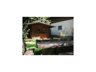 Holzhütte und -sitzgruppe im Garten