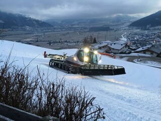 Pistenbully vorne an Chalet an der Piste