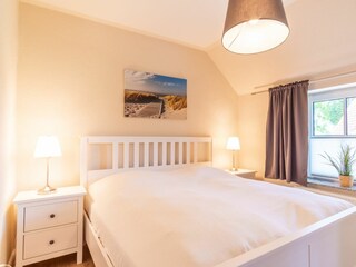 erstes Schlafzimmer mit Doppelbett und Kommode