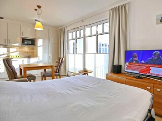 Wohnzimmer mit ausgeklappter Schlafcouch und TV