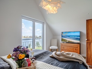 Schlafzimmer mit Smart TV und direktem Wasserblick