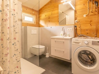 Das Badezimmer mit Dusche, WC und Waschmaschine
