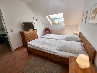 Schlafzimmer mit Doppelbett und TV